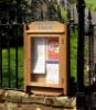 Noticeboard with engraved header sign at the top, located outside a church with church notices inside it, behind the locked glass panel